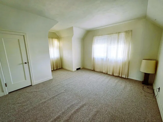 an empty room with window and bathroom