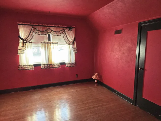 an empty room with wooden floor and a window