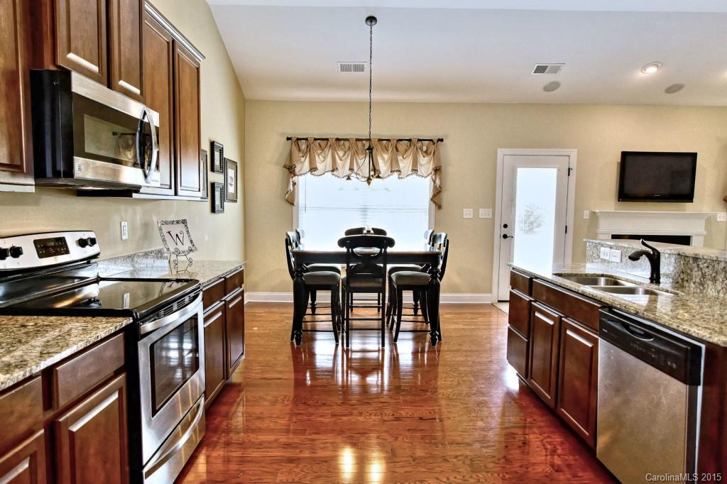 1628 Ridgehaven Road Waxhaw, NC 28173 - Photo 8 of 24 a kitchen with stainless steel appliances granite countertop a stove top oven a sink dishwasher a dining table and chairs with wooden floor