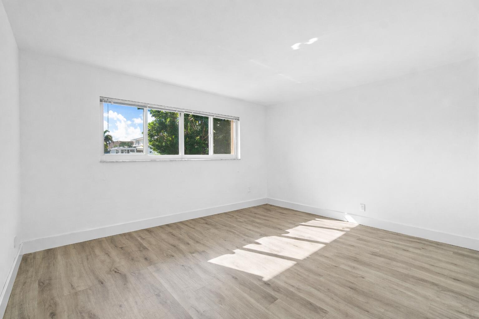 698 Northeast Spanish River Boulevard, Unit 140 Boca Raton, FL 33431 - Photo 7 of 21 an empty room with wooden floor and windows