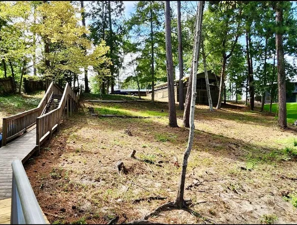 a view of deck with wooden floor and fence with trees in the background