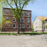 a view of a brick house with a yard and large tree