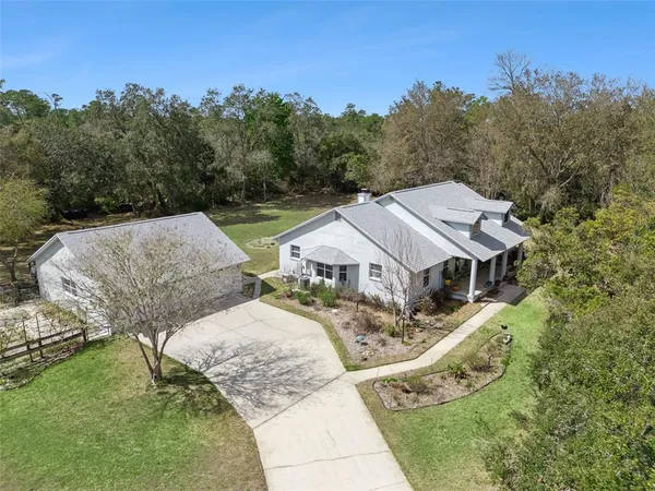 aerial view of a house with yard and trees in the background