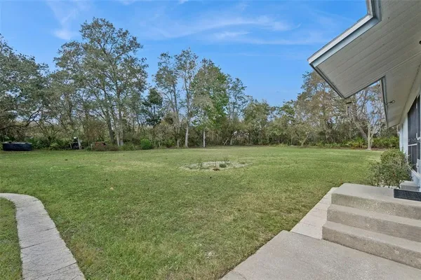 a aerial view of a house next to a big yard with plants and large trees