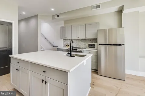 a kitchen with a sink a refrigerator and white cabinets