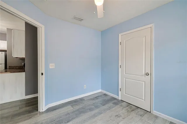 an empty room with wooden floor closet and windows