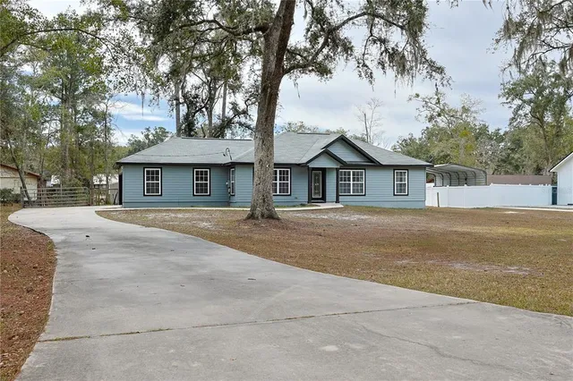 a front view of a house with a garden and tree