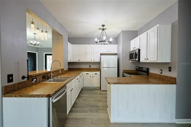 a large kitchen with granite countertop a white stove top oven a sink dishwasher and a refrigerator with wooden floor