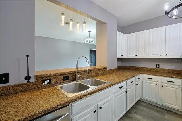 a kitchen with granite countertop a sink stainless steel appliances and cabinets