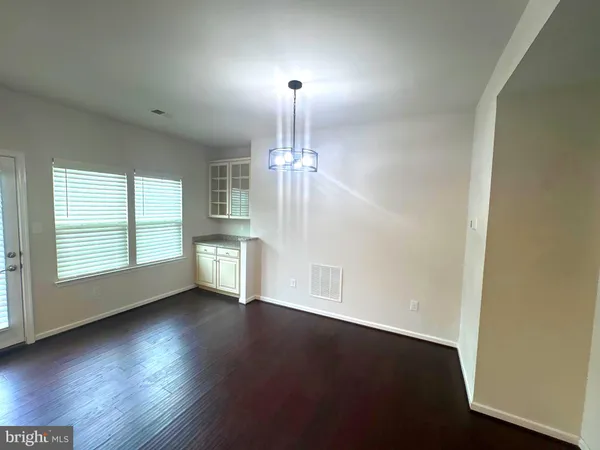 an empty room with wooden floor chandelier and windows