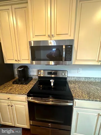 a kitchen with granite countertop a stove a sink and a microwave