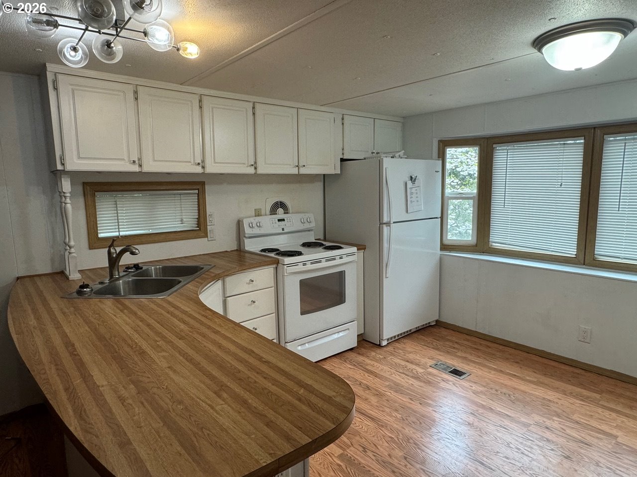 1600 Rhododendron Drive, Unit 293 Florence, OR 97439 - Photo 13 of 26 a kitchen with wooden floor and white appliances