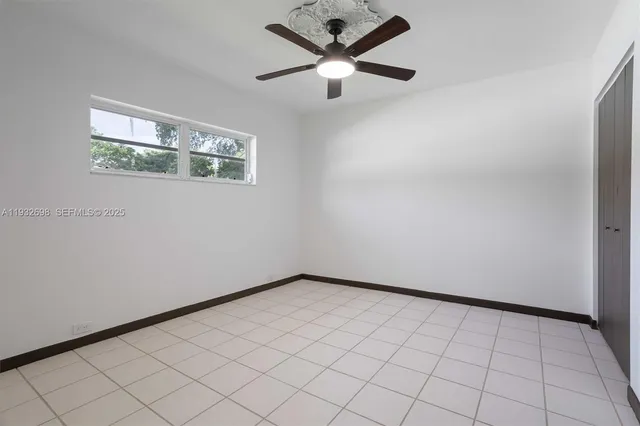 an empty room with a ceiling fan and window