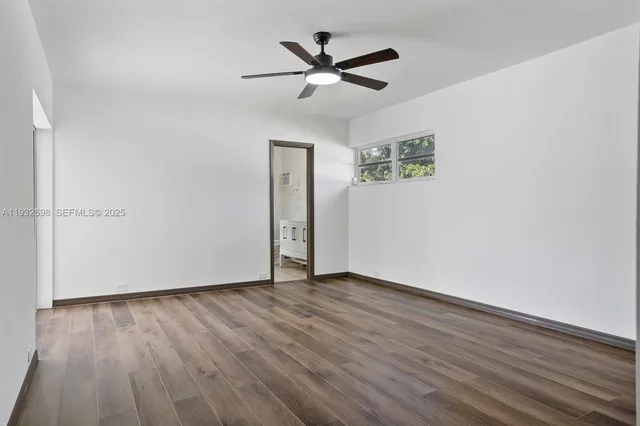 an empty room with wooden floor ceiling fan and windows