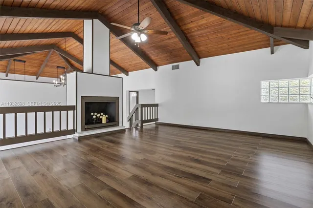 a view of an empty room with wooden floor a fireplace and a window