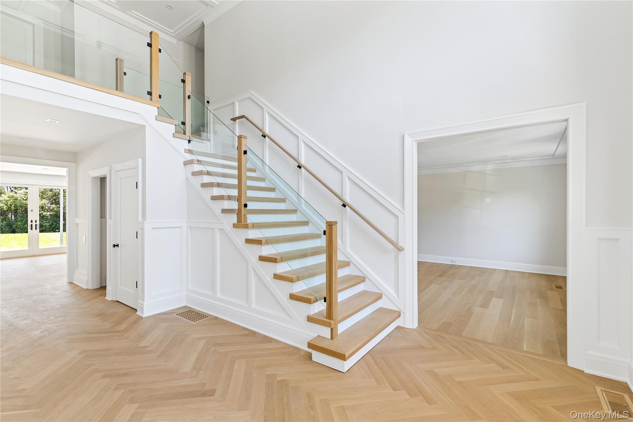 42 Mamaroneck Road Scarsdale, NY 10583 - Photo 9 of 47 A dramatic two-story foyer welcomes guests with herringbone hardwood floors and a striking modern staircase with contemporary glass railings.