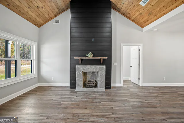 a view of an empty room with wooden floor fireplace and a window