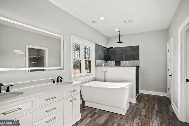 a spacious bathroom with a double vanity sink a mirror and a bathtub