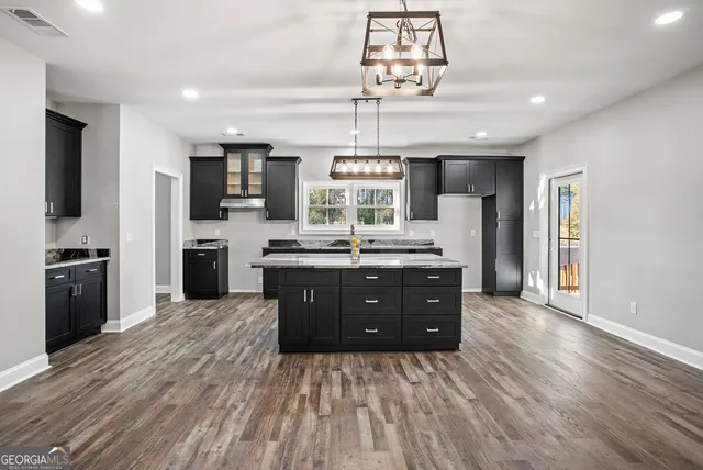 a kitchen with a chandelier stainless steel appliances cabinets and a counter top space