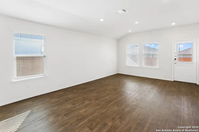 an empty room with wooden floor and windows