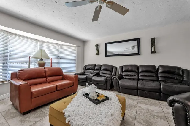 a living room with furniture ceiling fan and a window