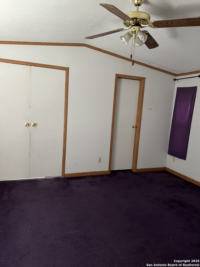 123 Chapman Street Pleasanton, TX 78064 - Photo 4 of 8 an empty room with wooden floor and fan