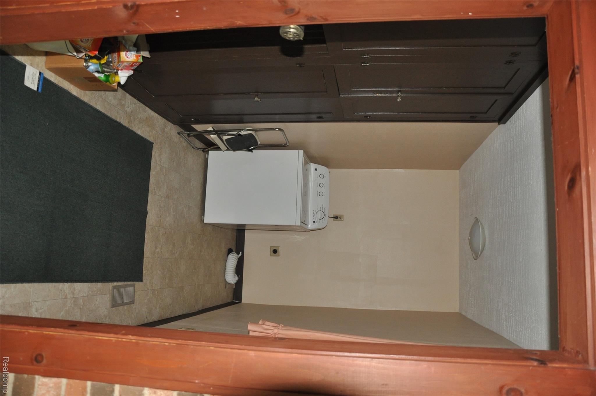 3954 Mayville Road Silverwood, MI 48760 - Photo 14 of 30 Dedicated laundry area featuring a white top-load washing machine, built-in dark brown cabinetry, and light-toned flooring