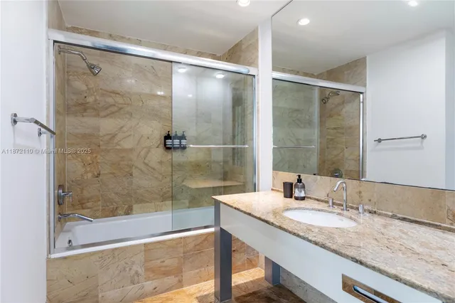 a bathroom with a granite countertop shower sink and mirror