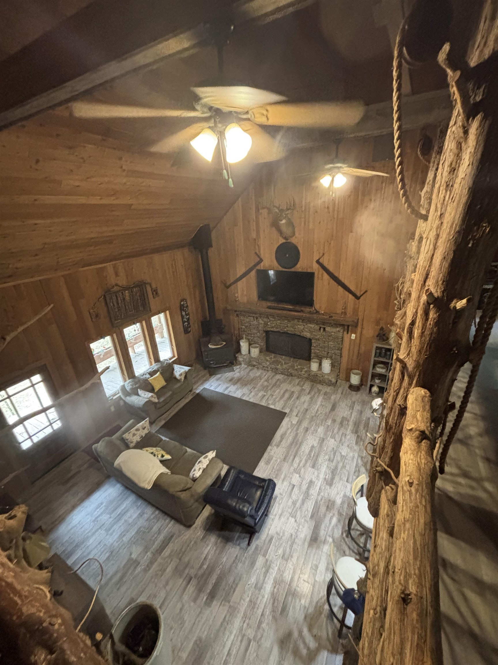 7462 Campground Road Drummonds, TN 38023 - Photo 28 of 31 Vaulted wood-paneled ceilings with ceiling fans, a stone-faced fireplace, wood-finish flooring, and multiple windows