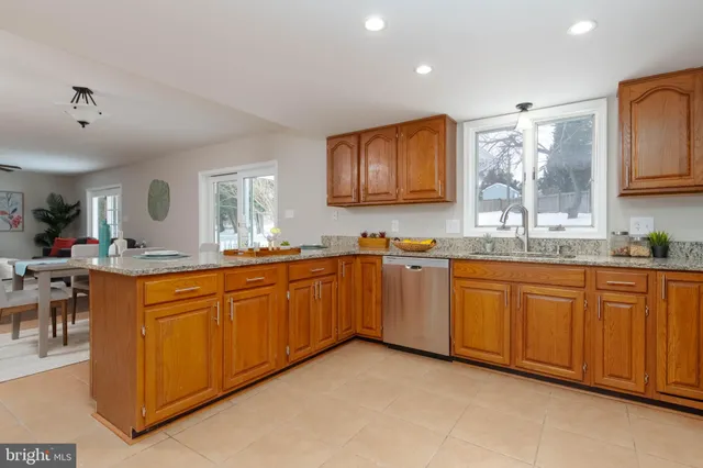 a large kitchen with granite countertop a sink white cabinets and stainless steel appliances