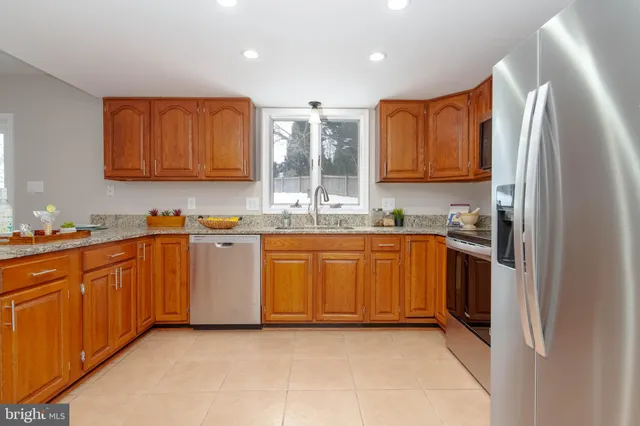 a kitchen with stainless steel appliances granite countertop a refrigerator a oven a sink with wooden cabinets and a granite counter tops