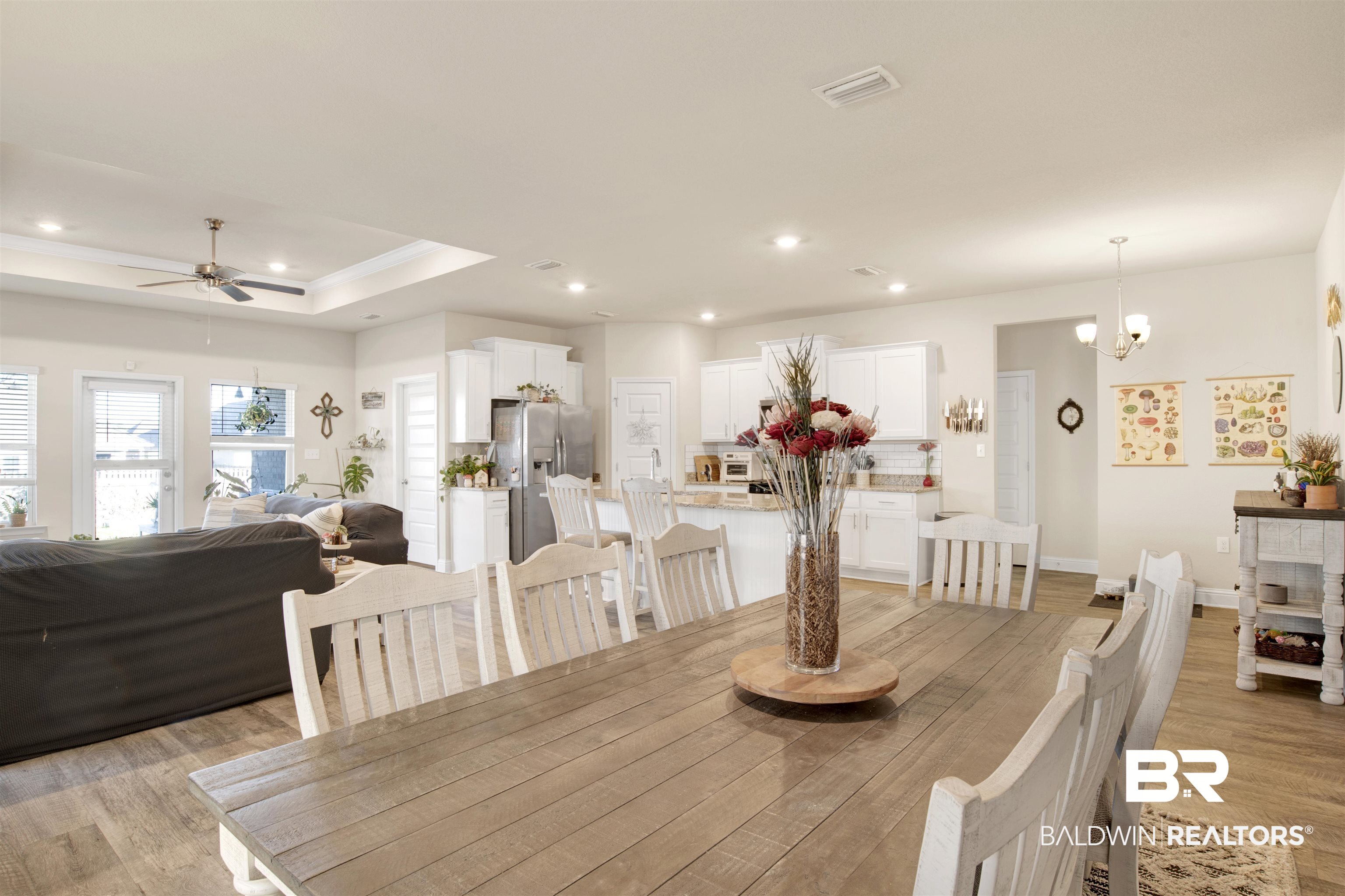 9622 Volterra Avenue Daphne, AL 36526 - Photo 15 of 31 Dining room with a tray ceiling, light hardwood / wood-style flooring, and ceiling fan with notable chandelier