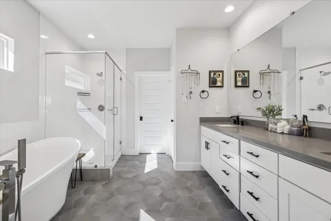 a spacious bathroom with a granite countertop tub sink a mirror a shower and vanity