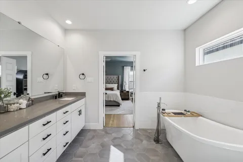 a bathroom with a granite countertop tub sink and mirror