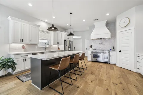 a kitchen with granite countertop a sink a counter space appliances and cabinets