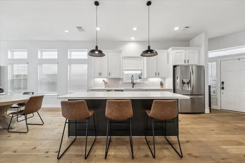 a kitchen with stainless steel appliances kitchen island granite countertop a dining table chairs and white cabinets