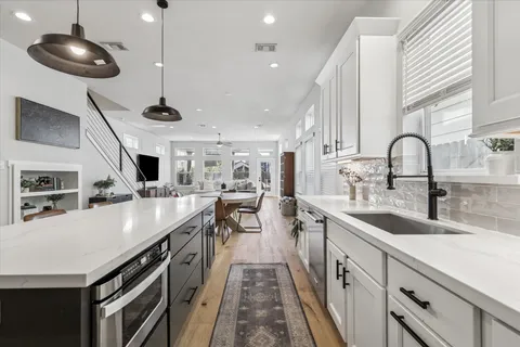 a kitchen with stainless steel appliances a sink a stove and a wooden floors