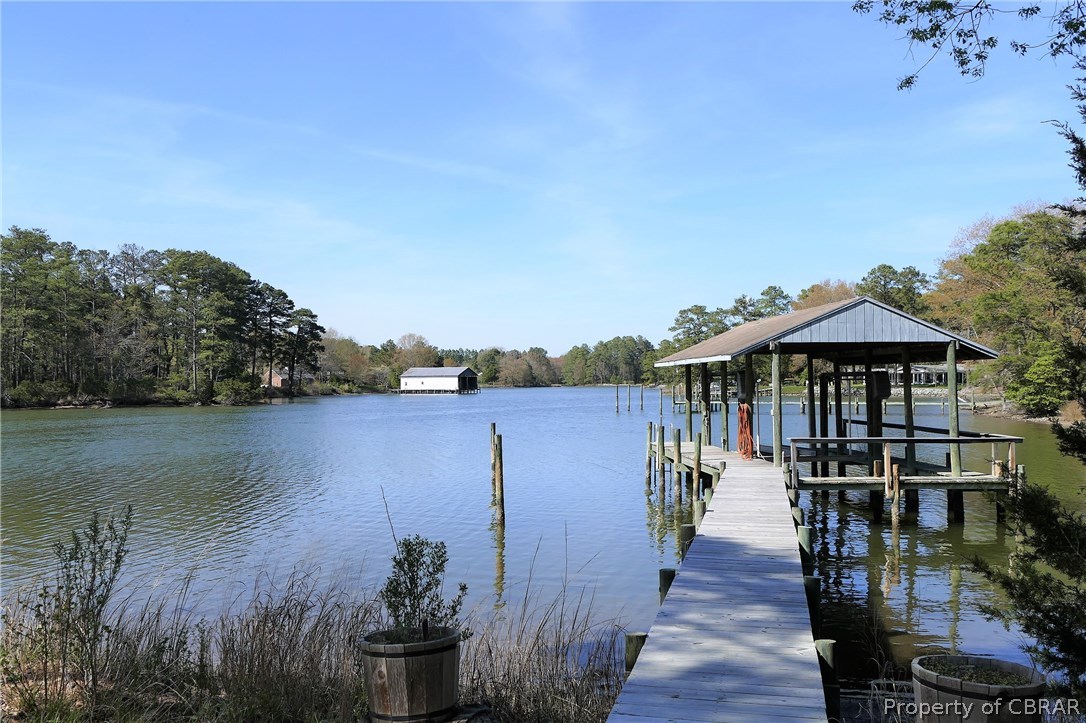 895 Holly Point Road Mathews, VA 23109 - Photo 2 of 47 a view of a lake with a table and chairs under an umbrella
