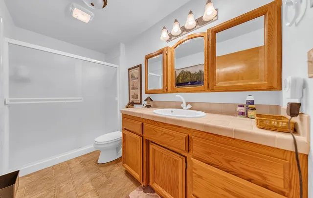 a bathroom with a granite countertop sink mirror vanity and toilet