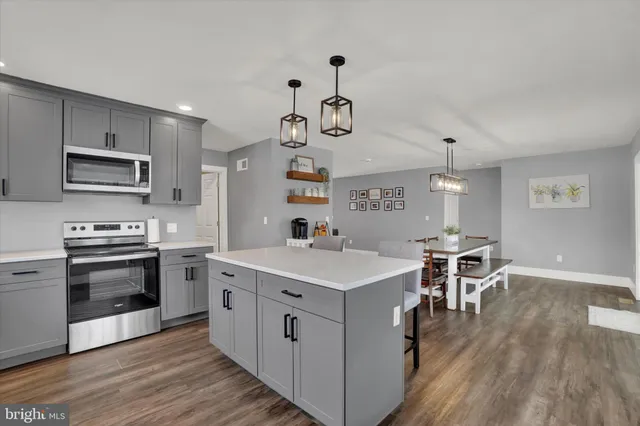 a kitchen with a sink stove cabinets and wooden floor