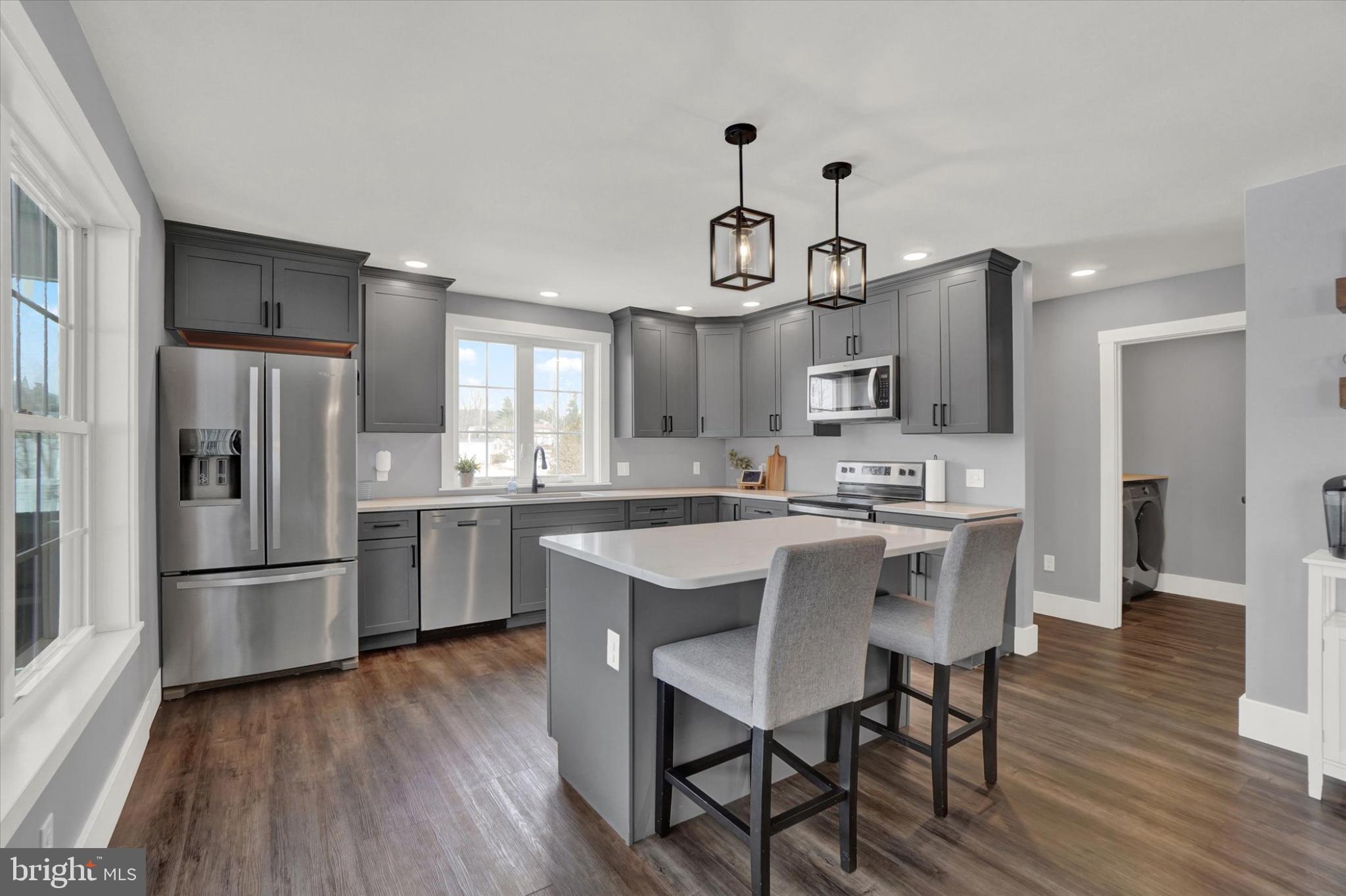 1048 Keller Road York, PA 17406 - Photo 9 of 28 a kitchen with a refrigerator a microwave oven a stove and a dining table with wooden floor