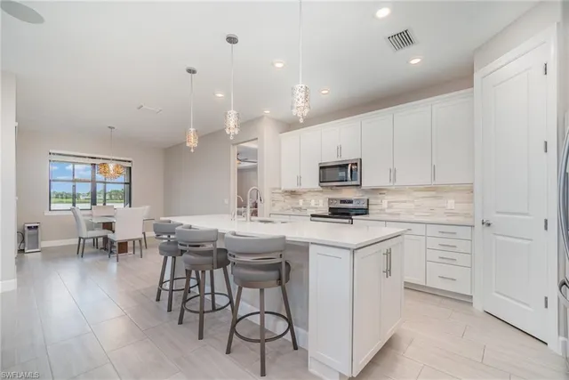 a kitchen with granite countertop white cabinets stainless steel appliances and a counter space