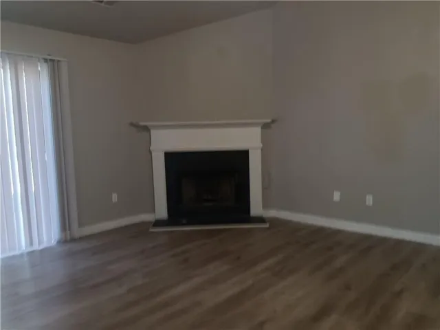 an empty room with wooden floor fireplace and windows
