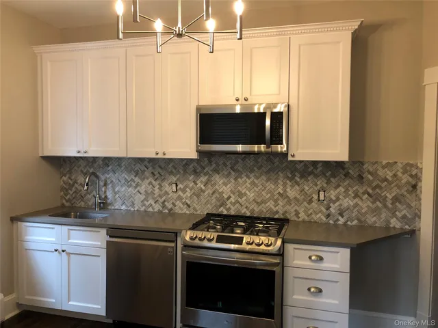 a kitchen with stainless steel appliances white cabinets and a stove top oven