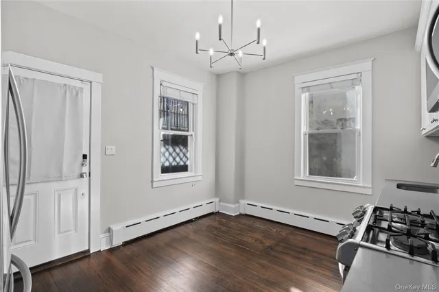 an empty room with wooden floor cabinet and windows