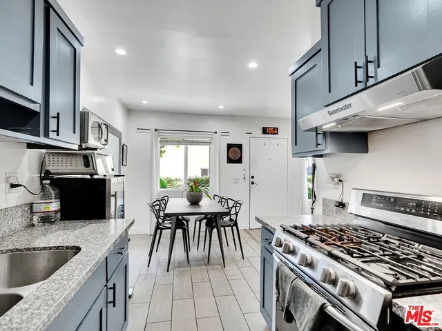 a kitchen with granite countertop a sink stainless steel appliances and white cabinets