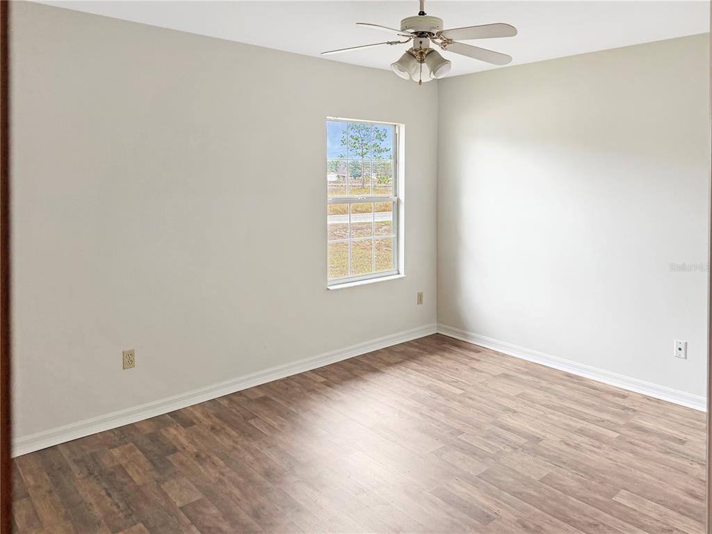 5730 Southeast 41st Street Ocala, FL 34480 - Photo 7 of 27 an empty room with wooden floor chandelier fan and windows