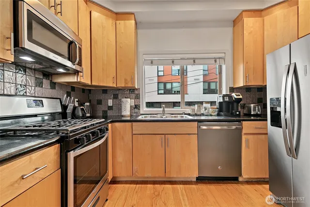 a kitchen with stainless steel appliances granite countertop a stove a sink and a refrigerator