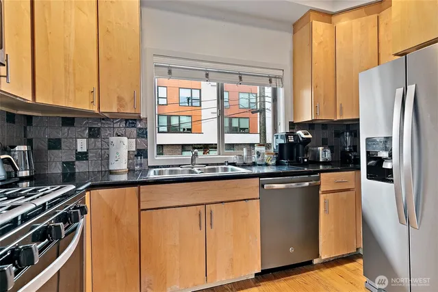 a kitchen with stainless steel appliances a sink cabinets and a window