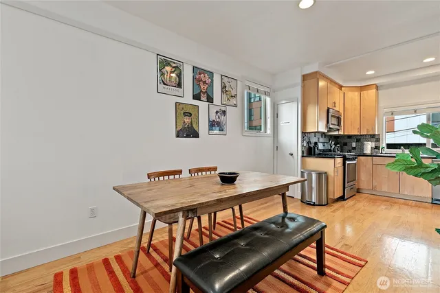 a kitchen with stainless steel appliances granite countertop a stove top oven a sink a dining table and chairs with wooden floor